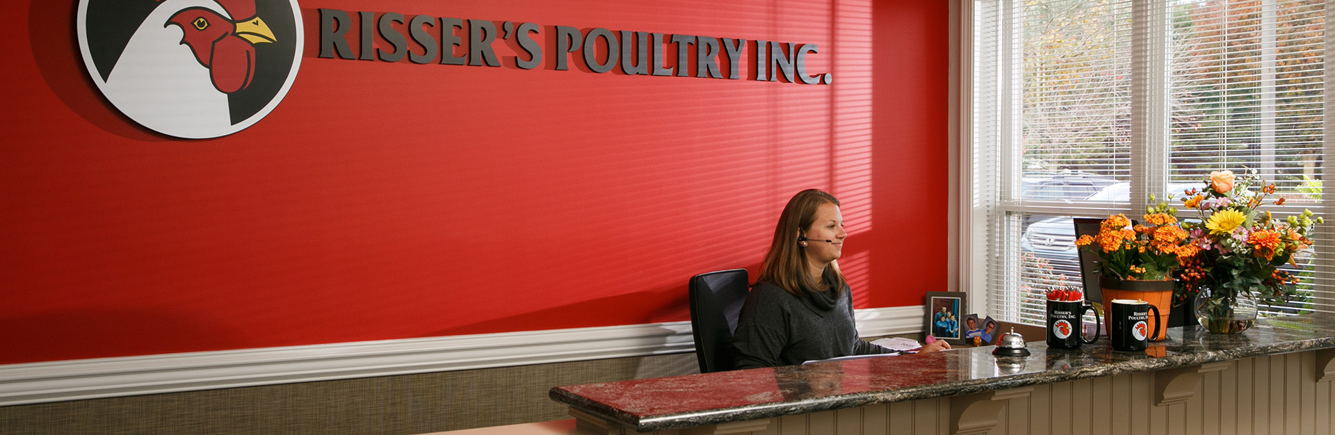 Three receptionists standing in front of Risser's Poultry, Inc. wall